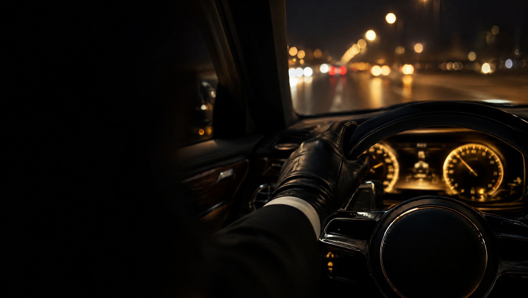 Chauffeur's gloved hand on the steering wheel at night